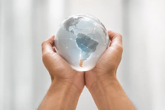 Hands holding a glass globe showing South America